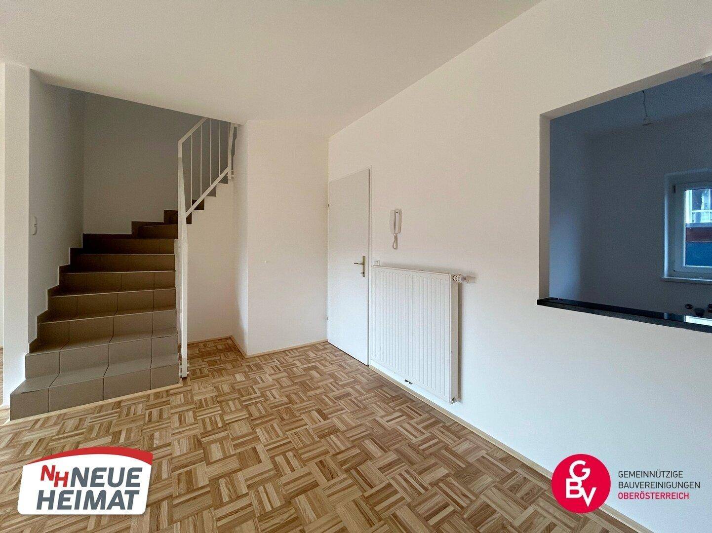 Heller Wohnbereich mit Parkettboden und Treppe, bietet eine offene und einladende Atmosphäre.