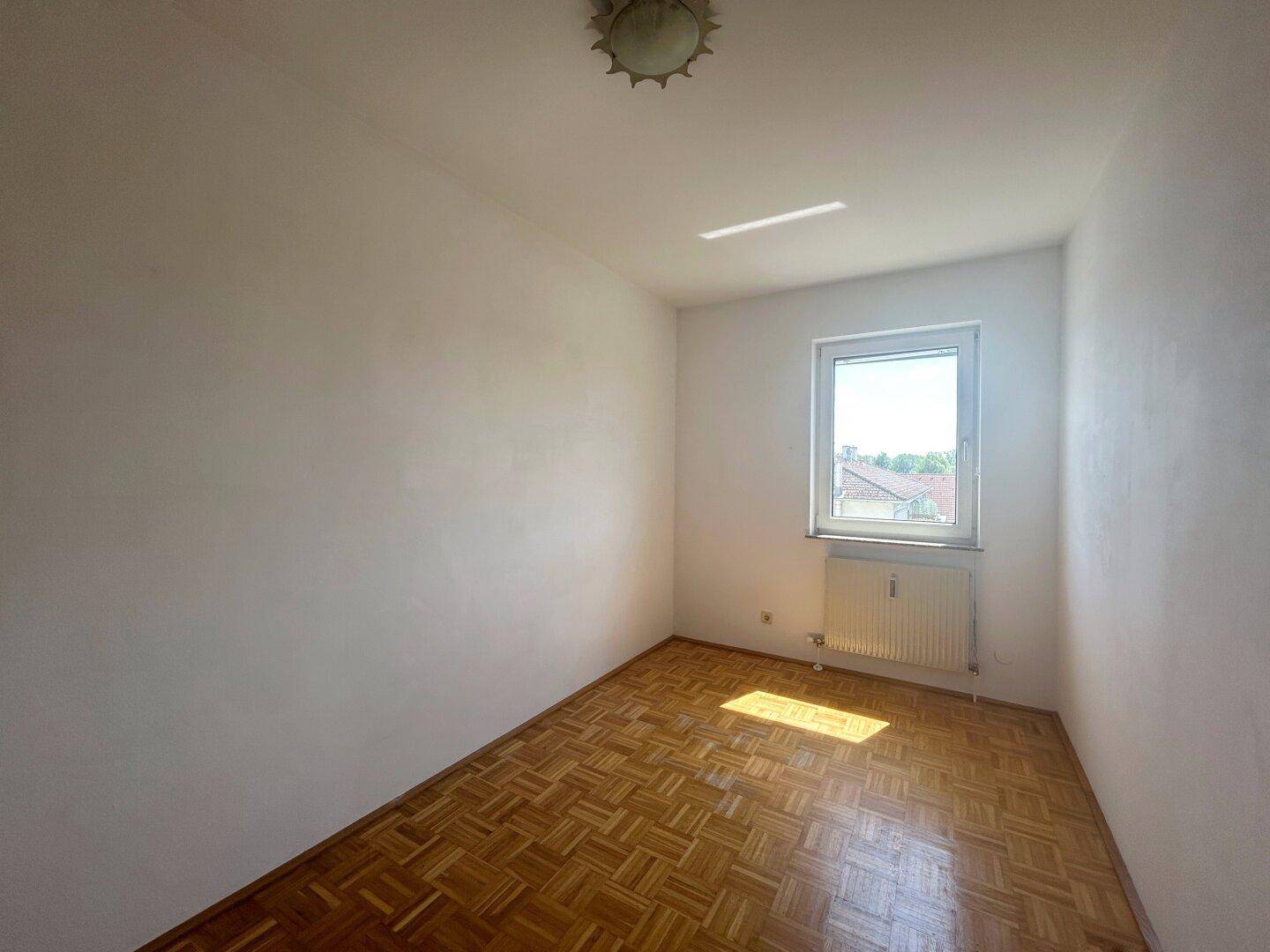 Kleines, helles Zimmer mit Parkettboden und einem Fenster, ideal als Kinder- oder Arbeitszimmer.