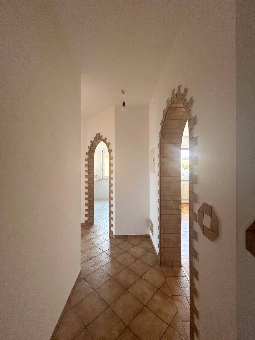 Heller Flur mit Fliesenboden und mehreren dekorativen Ziegelbögen, die Räume verbinden.