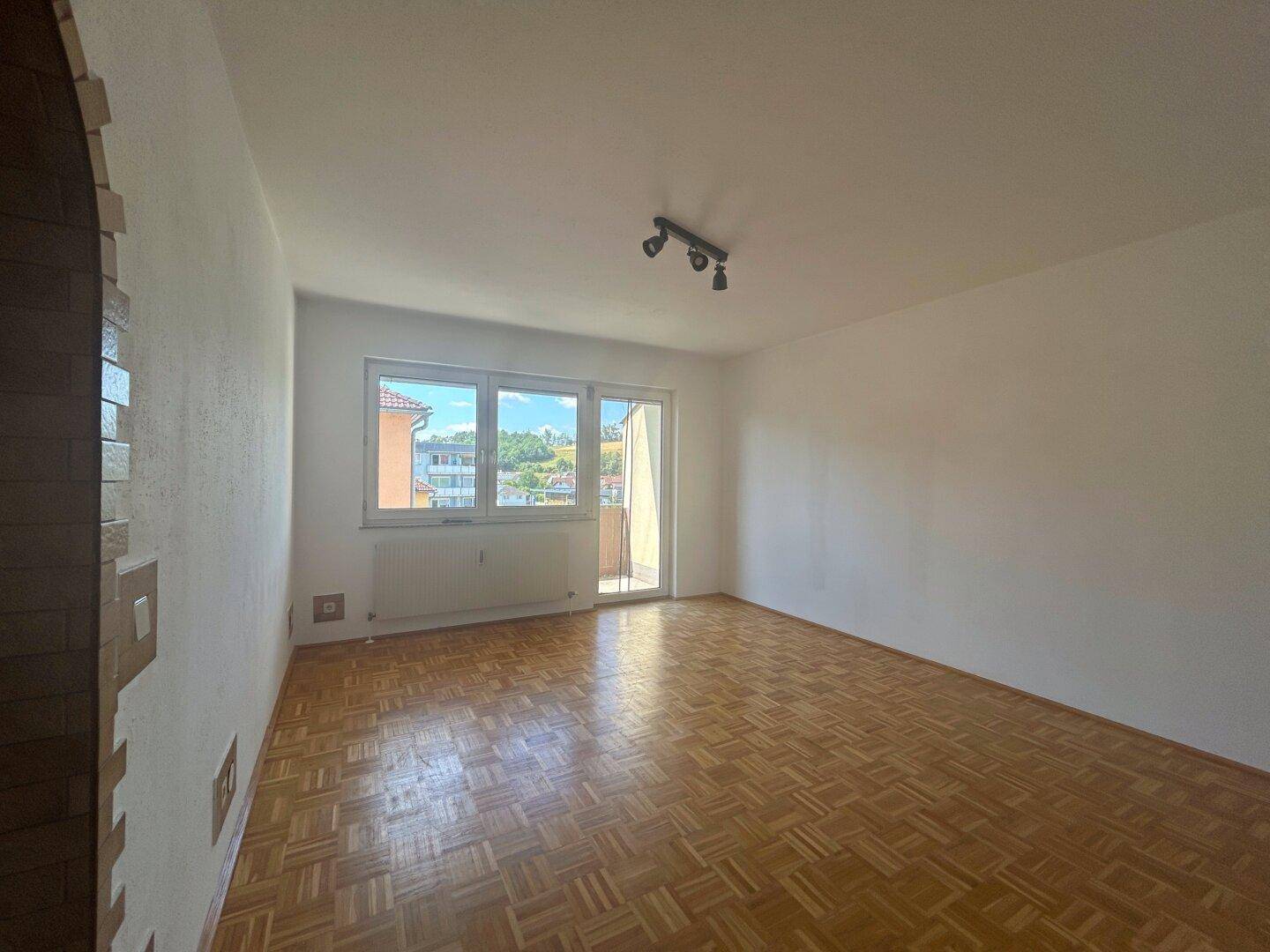 Helles Zimmer mit Parkettboden und Zugang zum Balkon, bietet viel natürliches Licht.