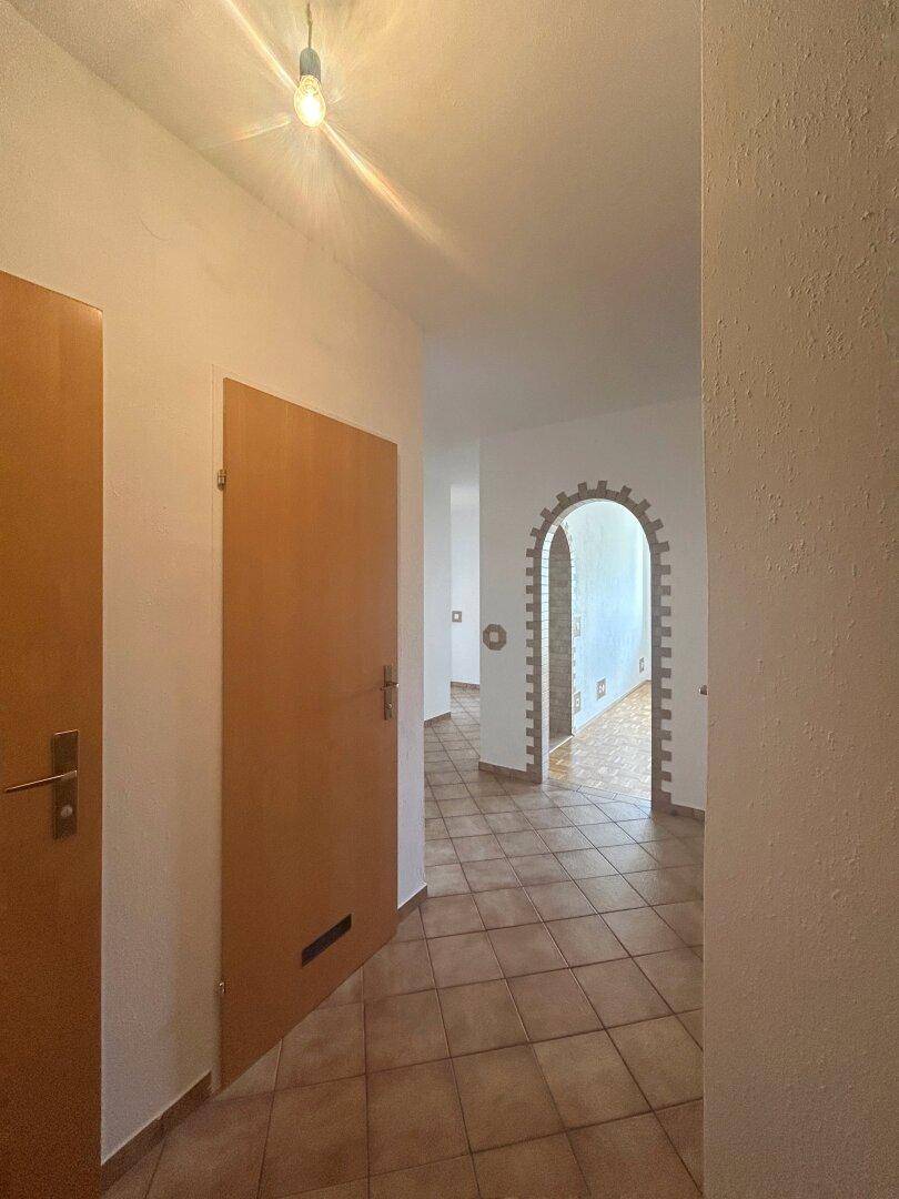 Flur mit Fliesenboden und Holztüren, der zu verschiedenen Bereichen der Wohnung führt.