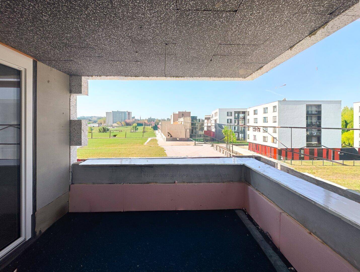 Unfertiger Balkon mit Blick auf umliegende Gebäude und Grünflächen.
