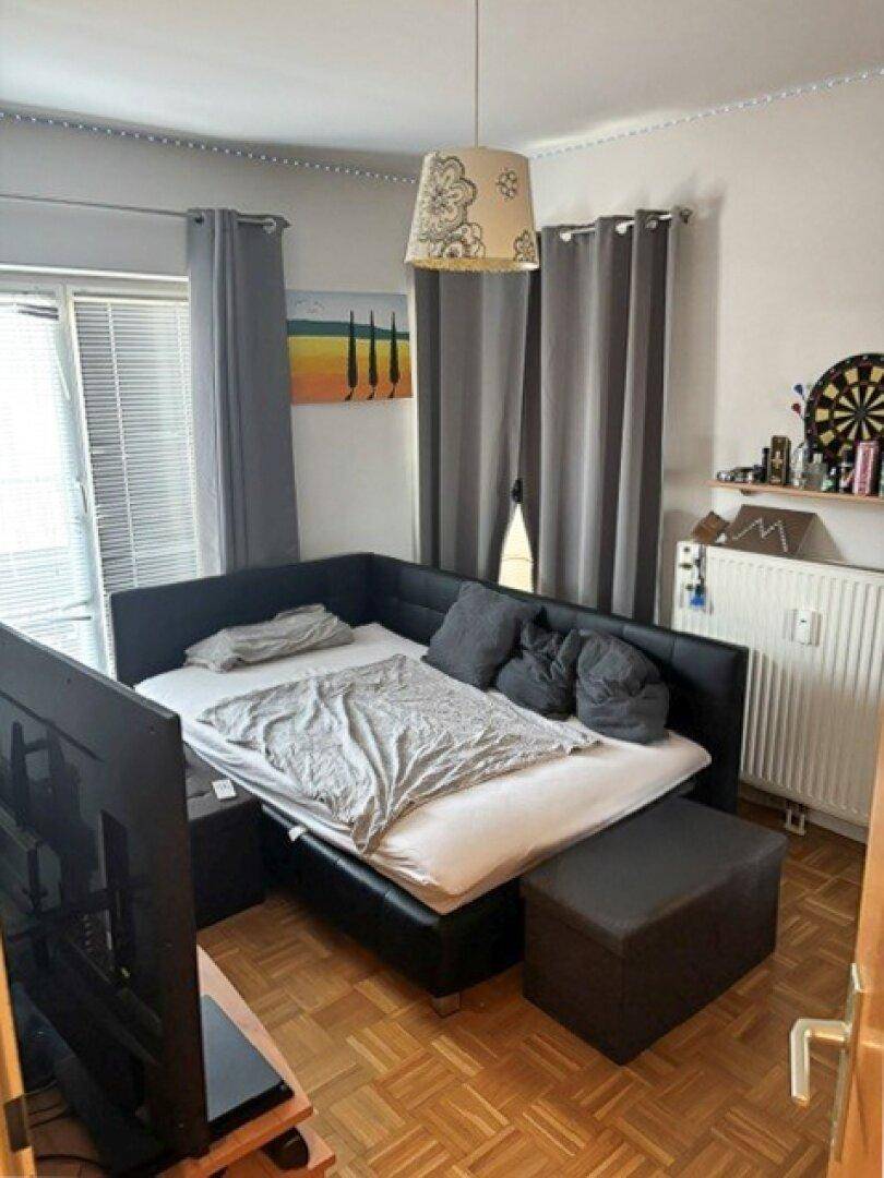 Schlafzimmer mit Eckbett, Fernseher und Zugang zu einem Balkon oder einer Terrasse.