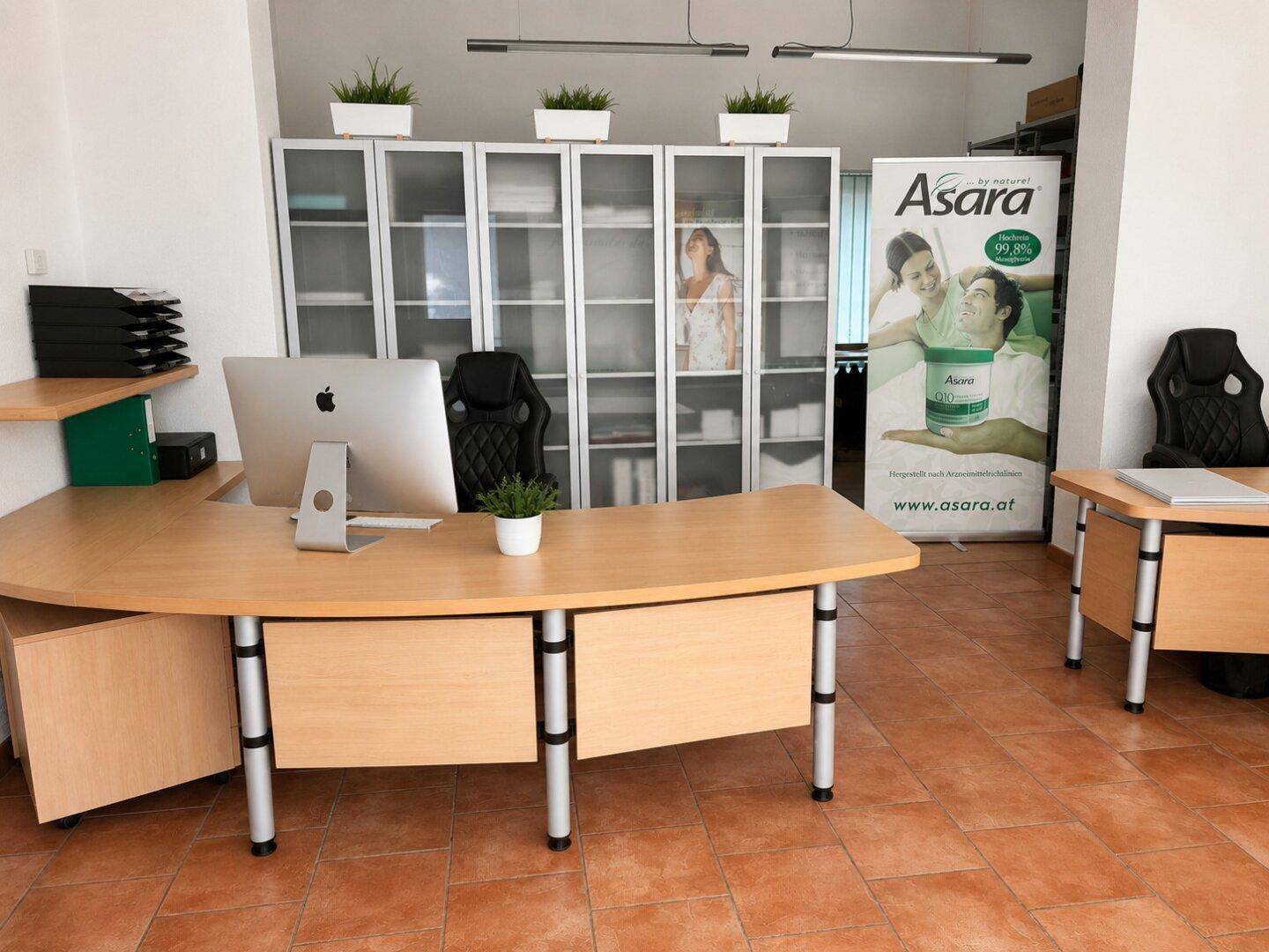 Helles Büro mit modernem Schreibtisch, Bürostühlen, Aktenschränken und Terrakotta-Fliesenboden.