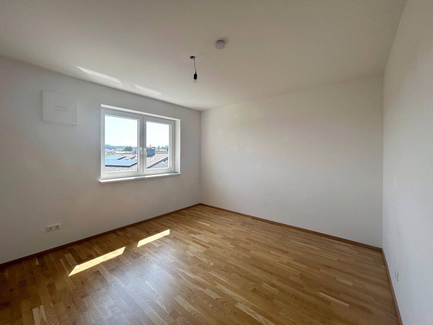 Helles Schlafzimmer mit Parkettboden und Blick auf die Umgebung, ideal für erholsame Nächte.