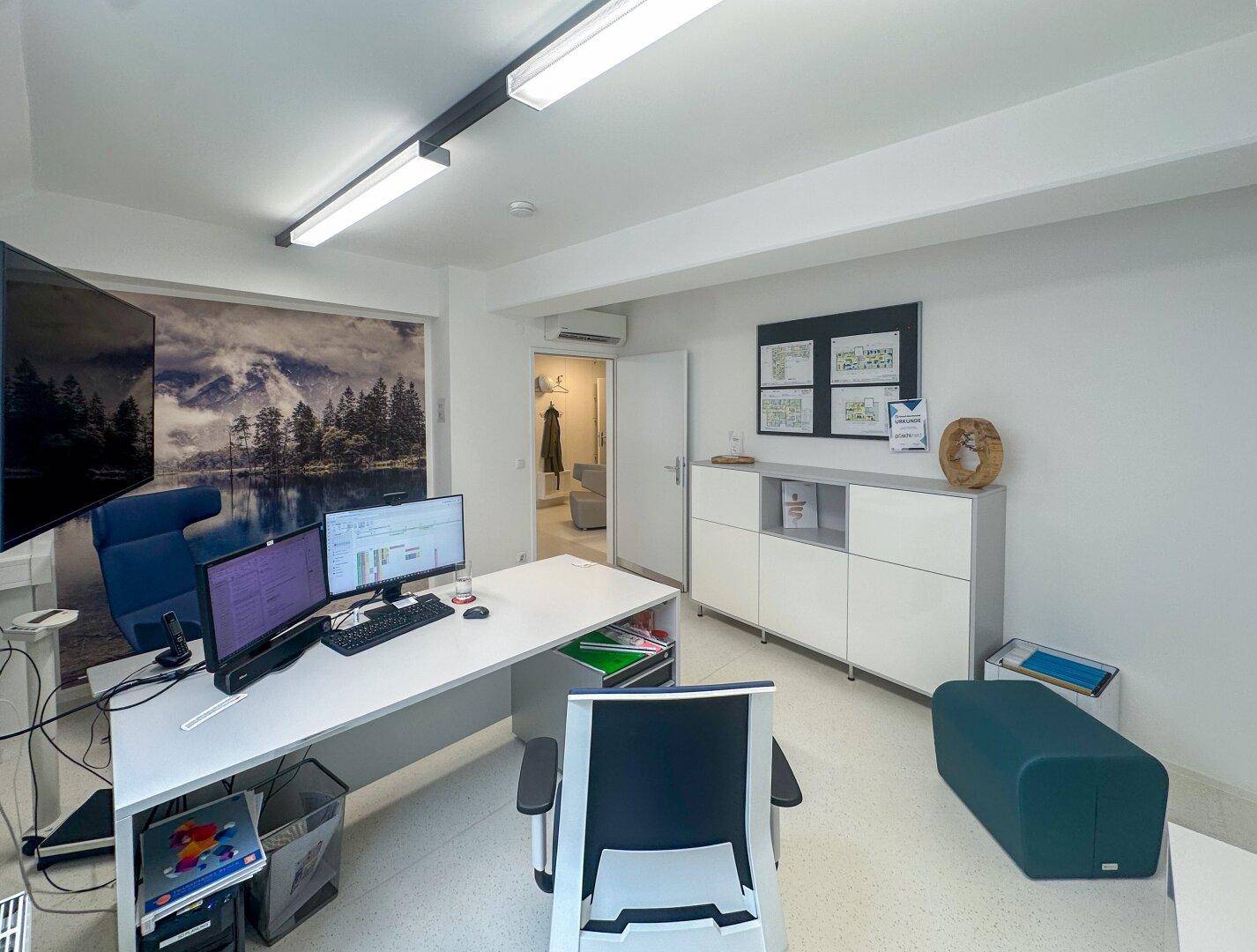 Modernes Büro mit Schreibtisch, Bürostuhl, Stauraum und Blick in den Flur.