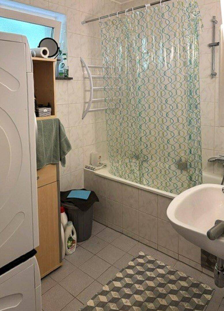 Badezimmer mit Badewanne, Waschbecken, Fenster und einer Waschmaschine.