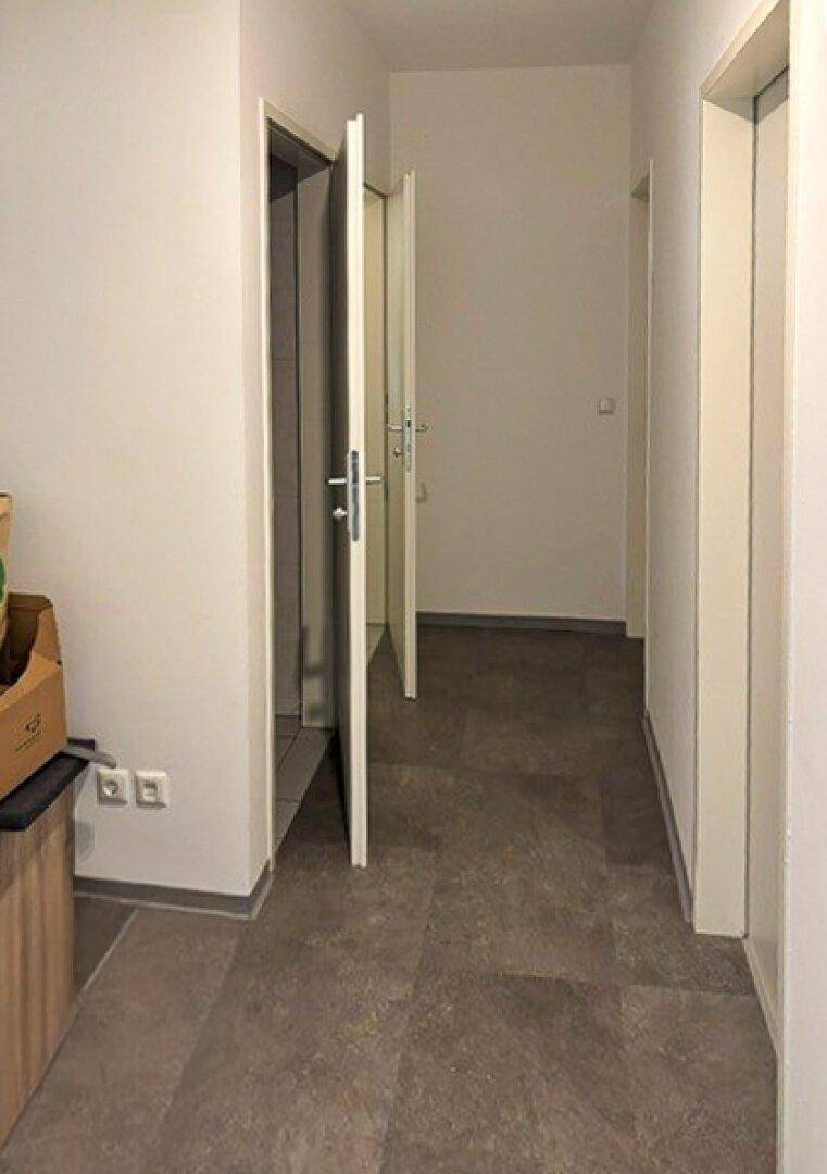 Heller Flur mit Fliesenboden und mehreren Türen, die zu verschiedenen Räumen führen.