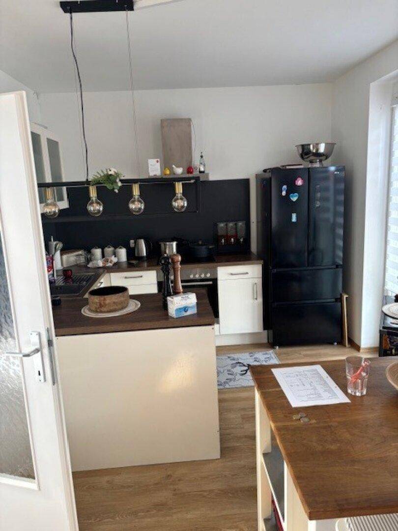 Moderne Küche mit schwarzen Geräten, weißen Schränken, Holzarbeitsplatte und einer kleinen Kücheninsel.