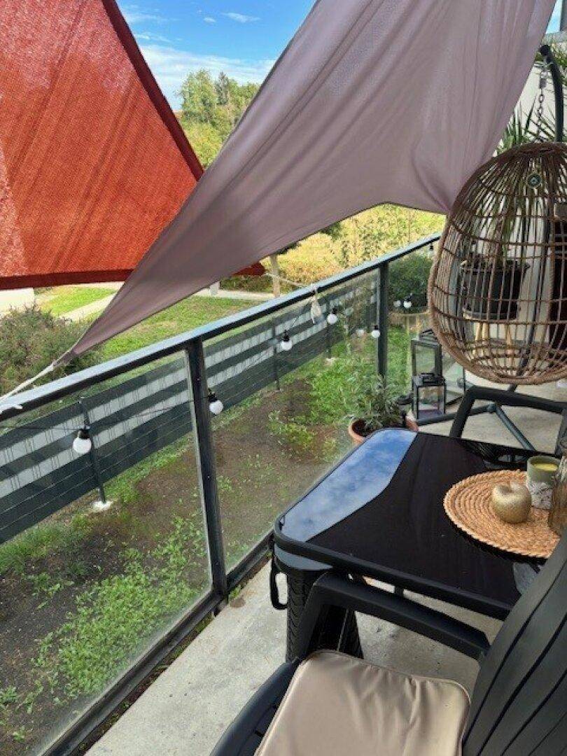 Gemütlicher Balkon mit Sitzgelegenheiten, Sonnenschutz und Blick ins Grüne.
