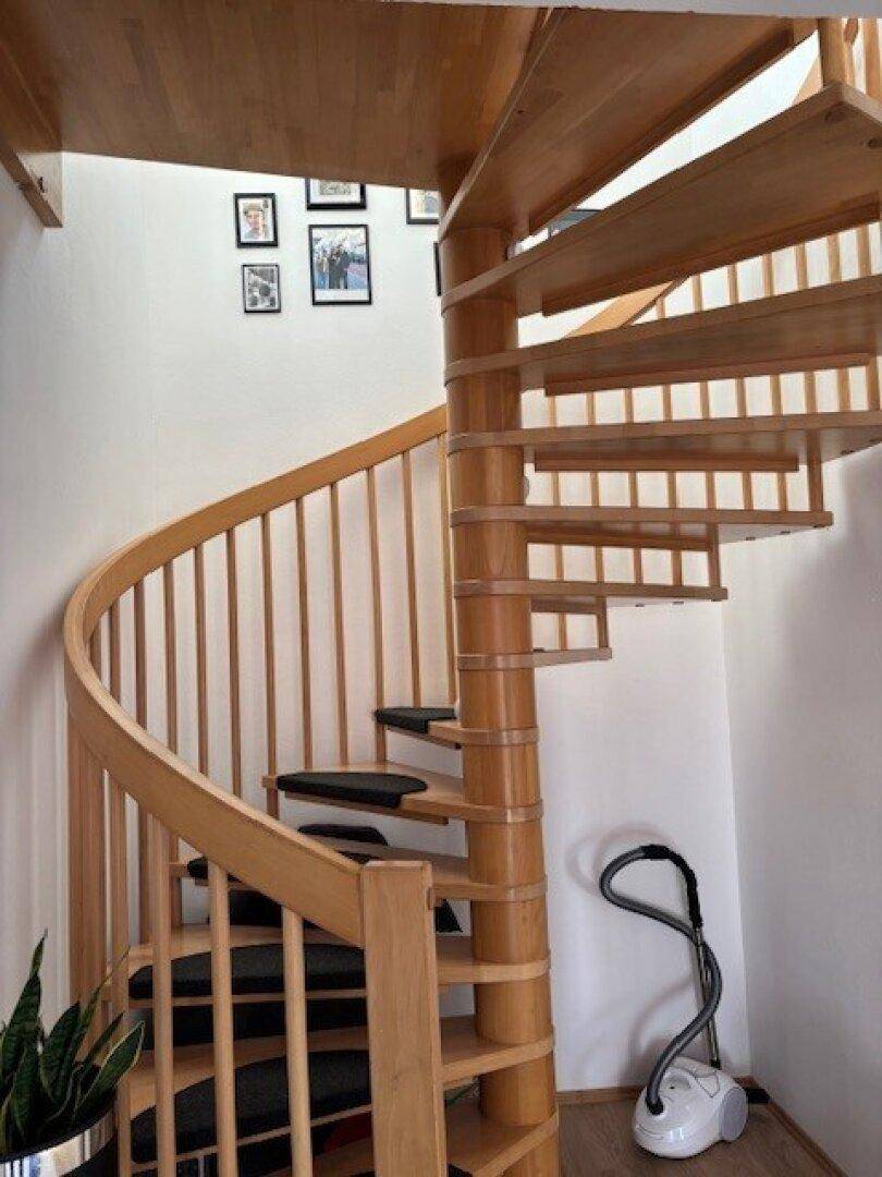 Elegante Holzwendeltreppe mit hellen Stufen und einem geschwungenen Geländer.
