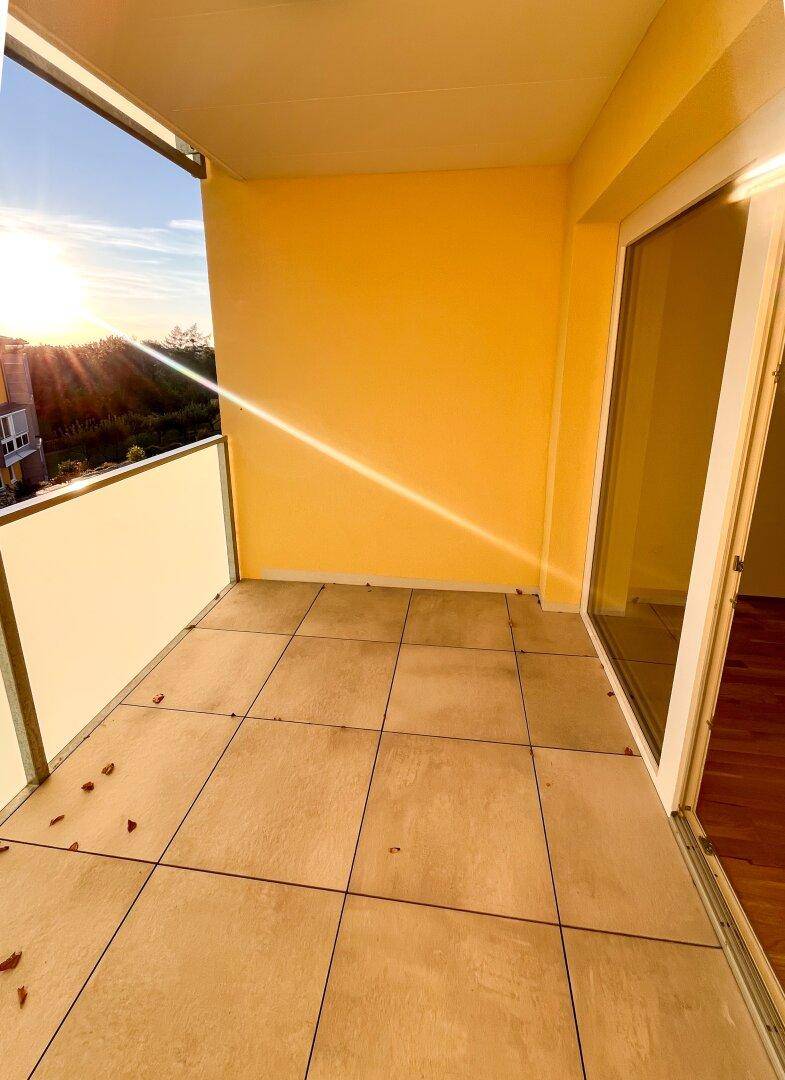 Sonniger Balkon mit Fliesenboden und gelben Wänden, ideal für entspannte Abende.