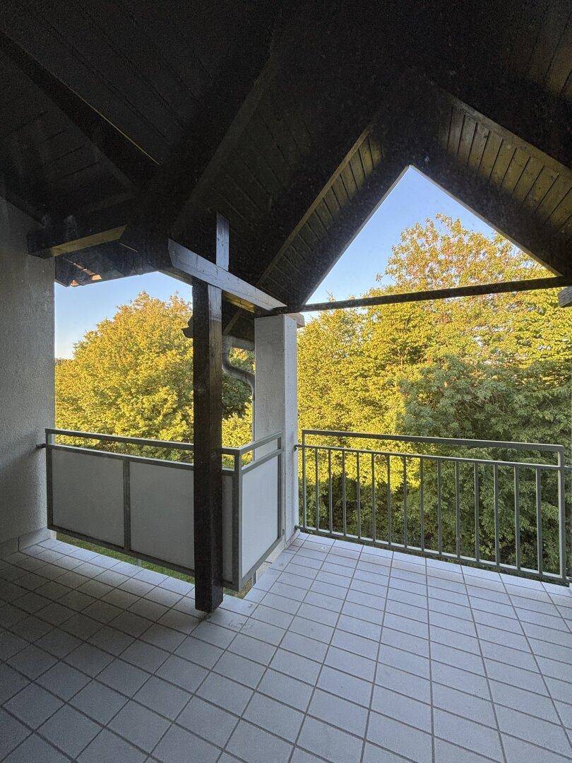 Überdachter Balkon mit Fliesenboden und einem schönen Blick ins Grüne.