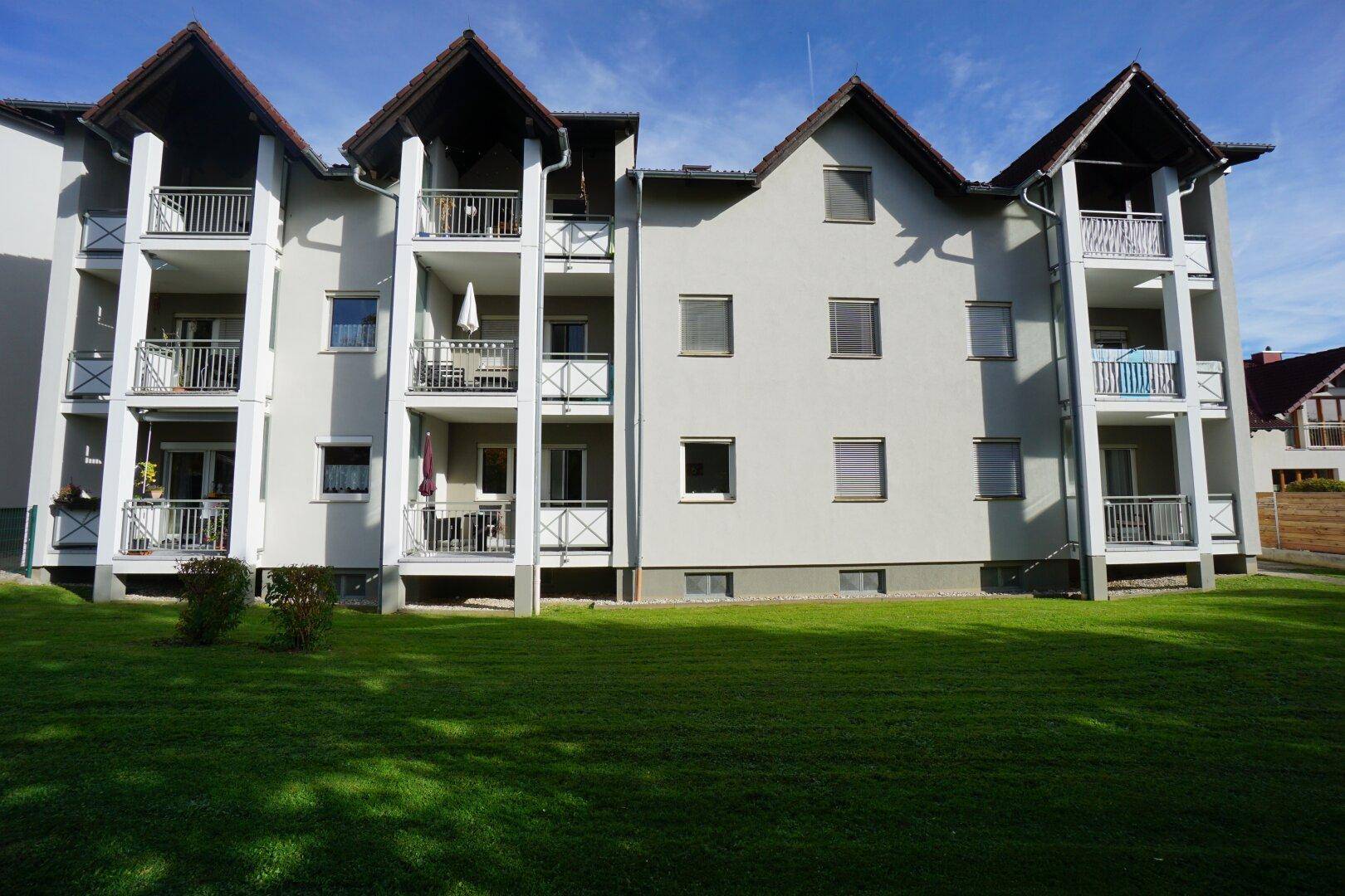 Modernes Mehrfamilienhaus mit mehreren Balkonen und einer gepflegten Rasenfläche.