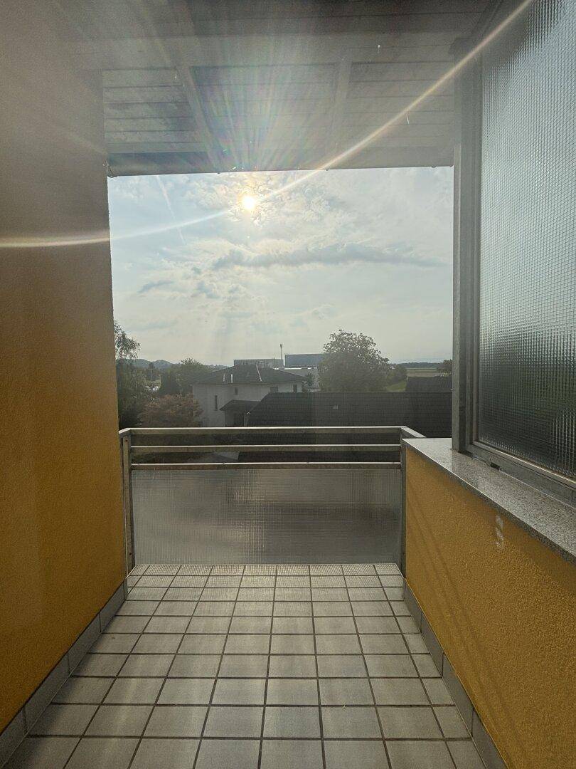 Kleiner Balkon mit Fliesenboden und weitem Blick über die Umgebung bei Sonnenschein.