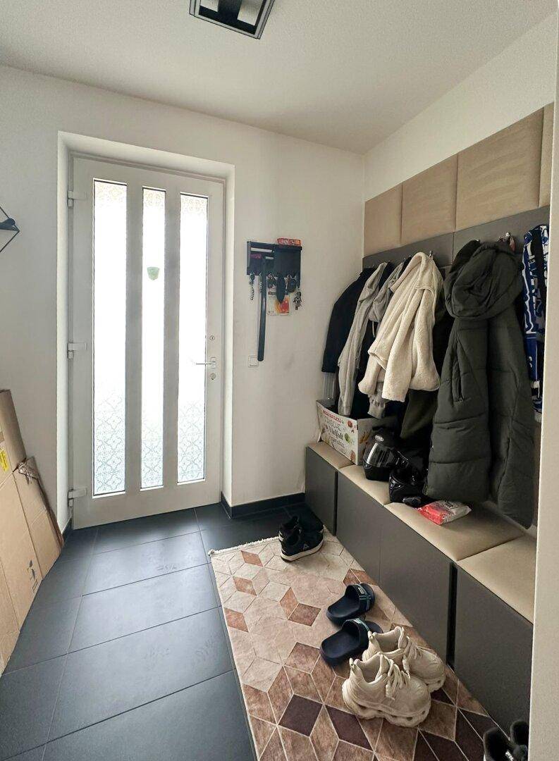 Eingangsbereich mit Fliesenboden, Garderobe und einer hellen Eingangstür.