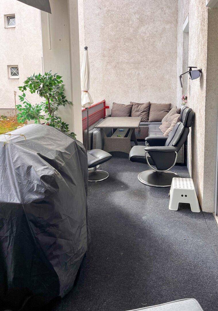 Möblierter Balkon mit Sitzgelegenheiten und Grill, ideal für entspannte Stunden im Freien.