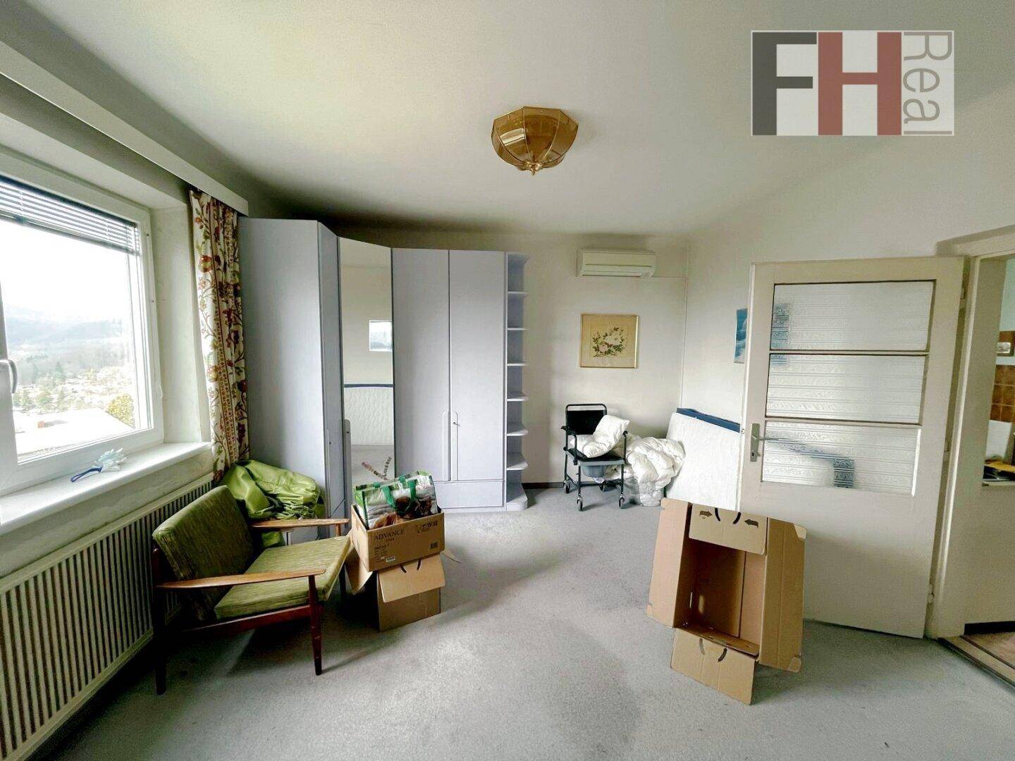 Schlafzimmer mit Teppichboden, Kleiderschrank und Blick auf die Landschaft durch das Fenster.