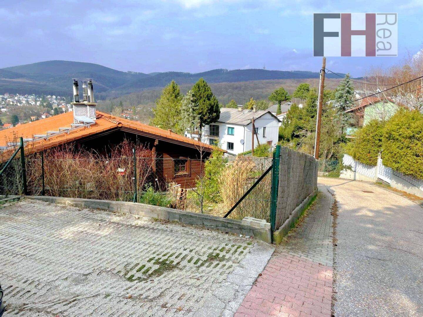 Zufahrtsstraße mit einem Haus im traditionellen Stil und Blick auf die Berge in der Ferne.
