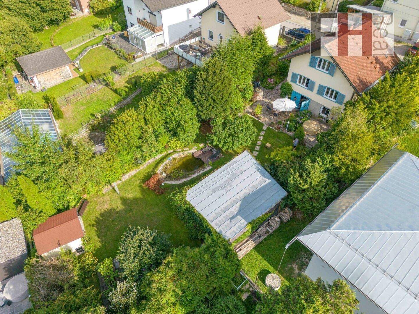 Luftaufnahme des Anwesens mit großem Garten, Teich, Nebengebäuden und umgebender Natur.