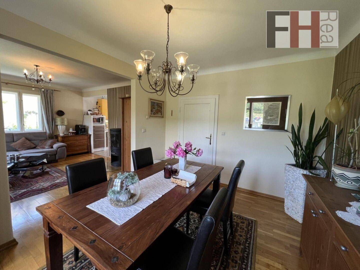 Heller Essbereich mit Holztisch und Stühlen, verbunden mit dem Wohnzimmer und Blick nach draußen.