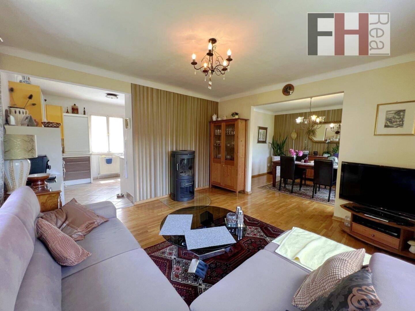 Gemütliches Wohnzimmer mit Sofa und Kaminofen, offen zum Essbereich und mit Zugang zur Küche.