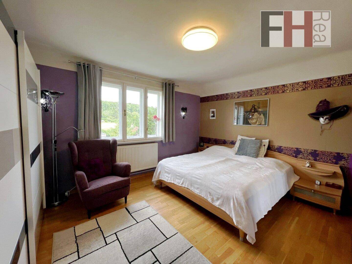 Gemütliches Schlafzimmer mit Holzboden, Doppelbett und Blick ins Grüne durch das große Fenster.