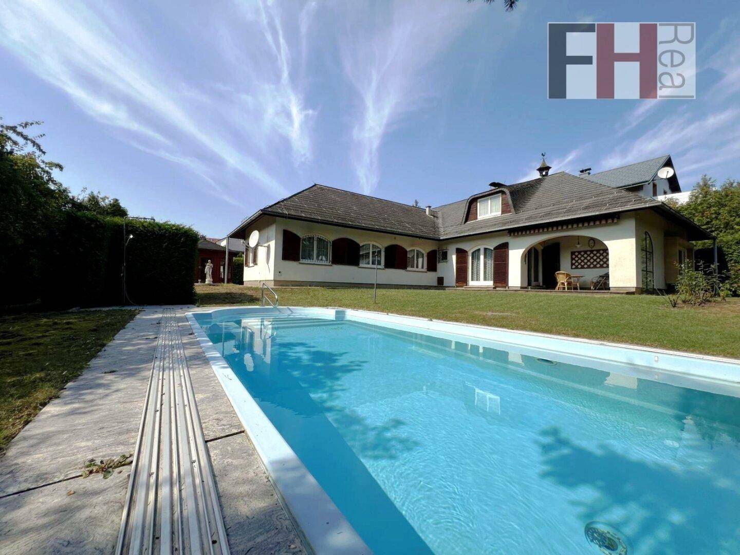 Langer Swimmingpool im grünen Garten mit Blick auf das charmante Wohnhaus.