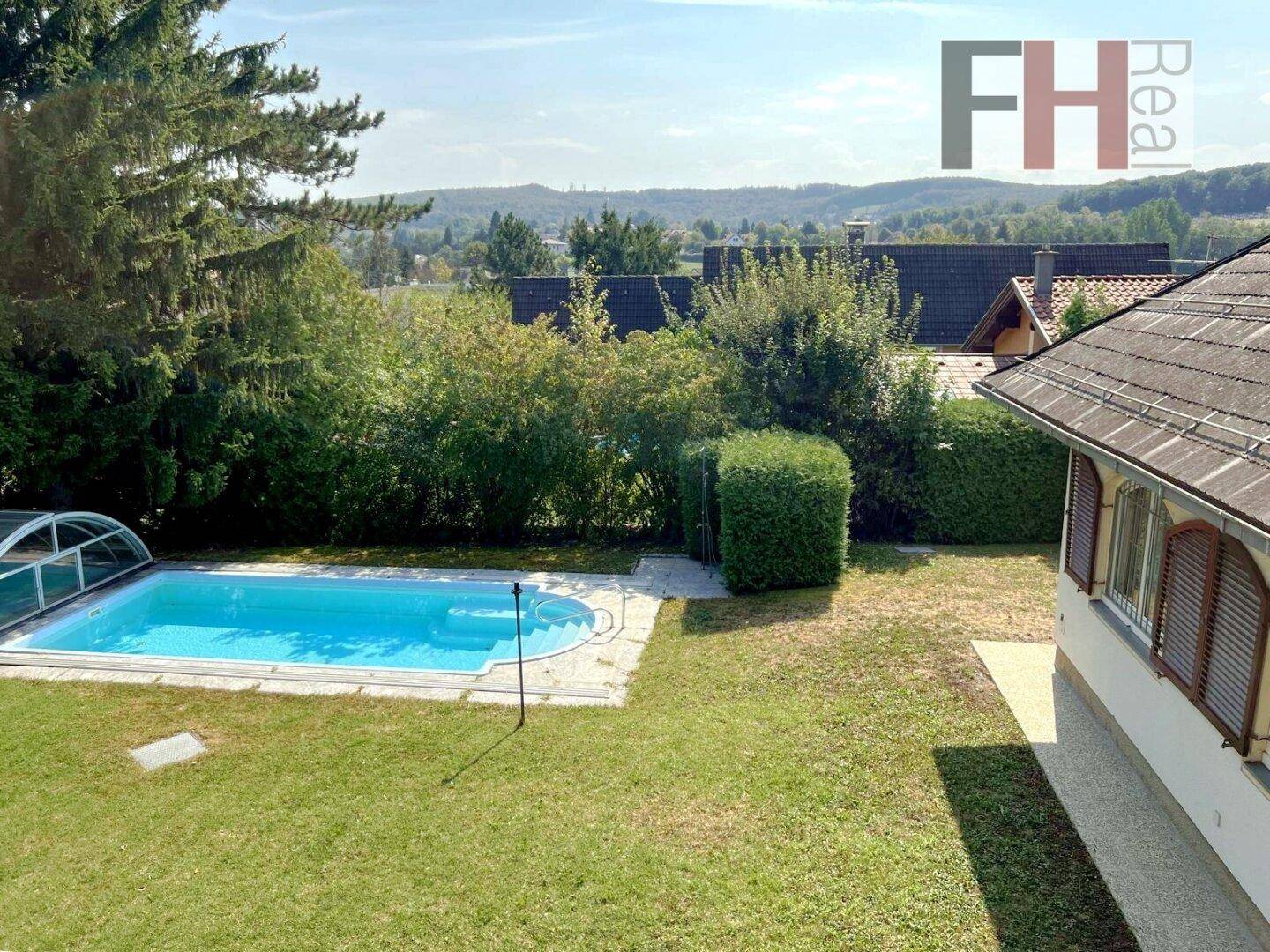 Garten mit Pool und weitem Blick über die hügelige Landschaft und umliegende Häuser.