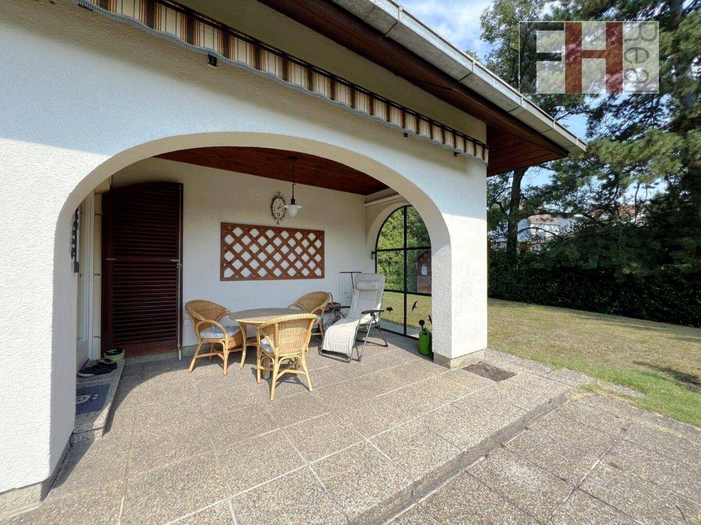 Gemütliche überdachte Terrasse mit Korbmöbeln, ideal für entspannte Stunden im Freien.