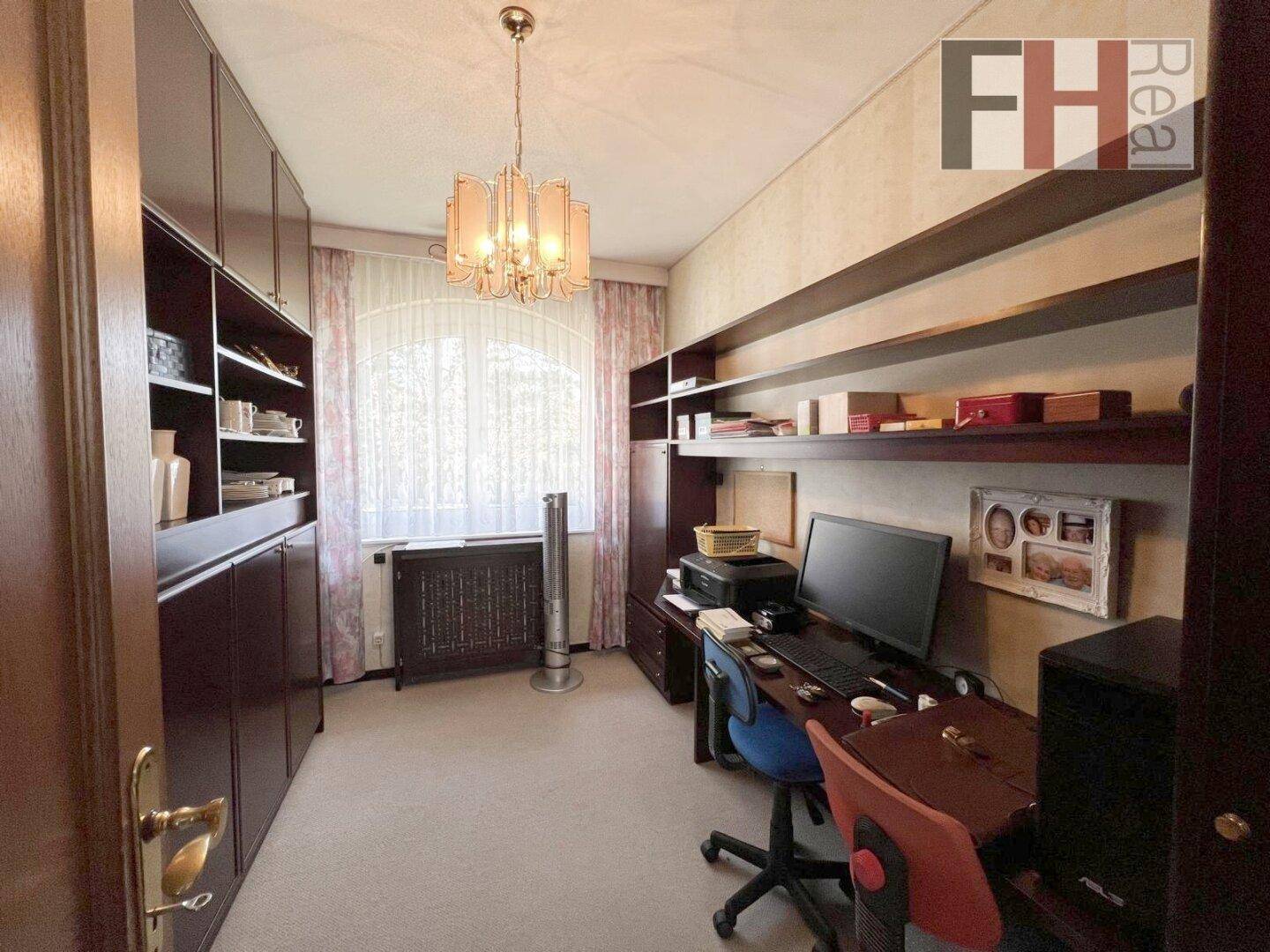 Funktionales Büro mit großem Schreibtisch, Regalen und Blick ins Grüne.