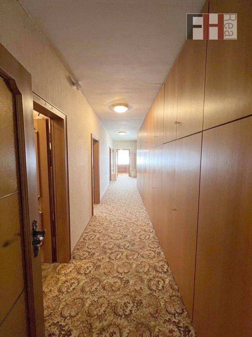 Langer Flur mit Teppichboden und integrierten Holzschränken für Stauraum.