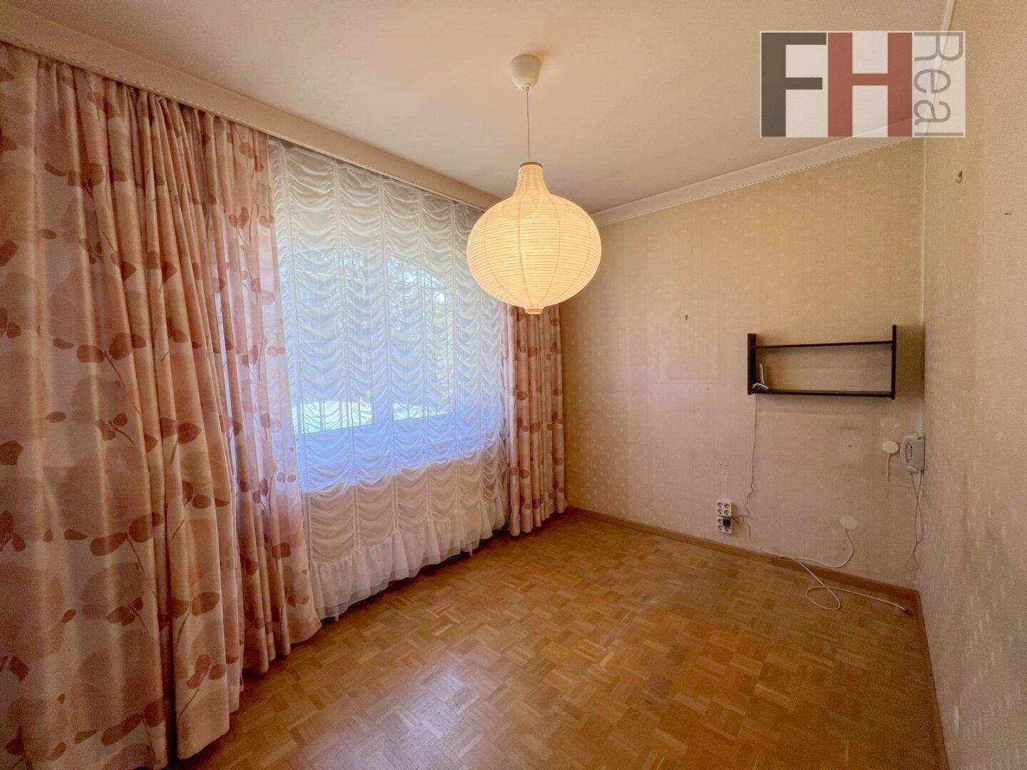 Helles Schlafzimmer mit Parkettboden und großem Fenster, bereit zur individuellen Gestaltung.