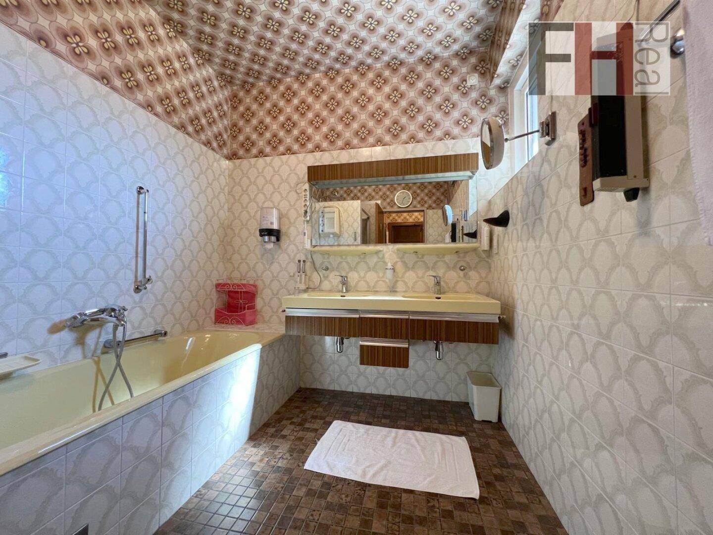 Geräumiges Badezimmer mit Doppelwaschbecken, Badewanne und Fliesen im 80er-Jahre-Stil.