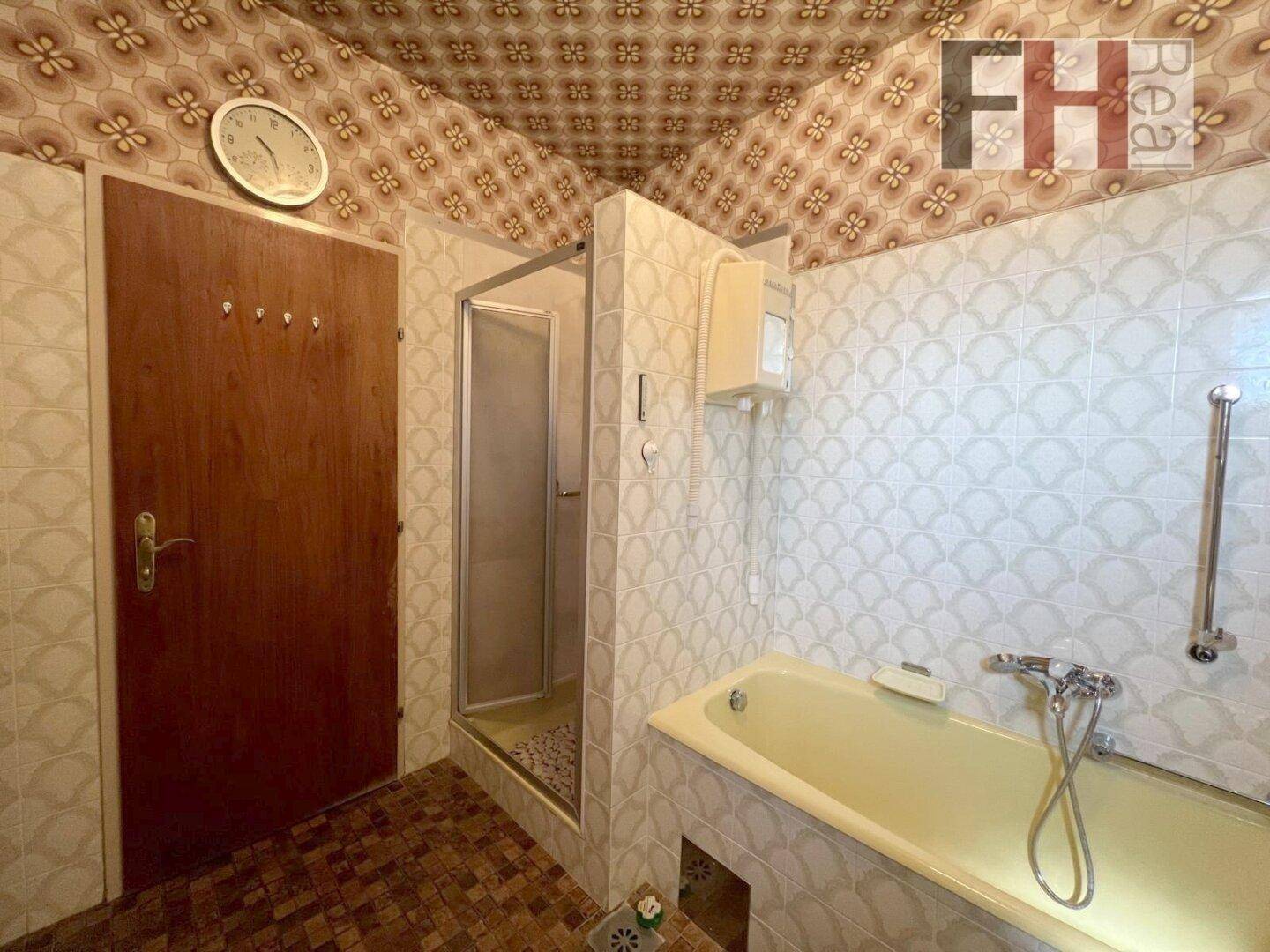 Badezimmer mit Badewanne, Duschkabine und Fliesen im Retro-Design.
