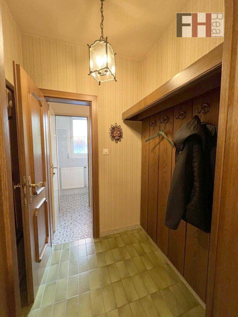 Eingangsbereich mit Garderobe und Fliesenboden, der zu weiteren Räumen führt.