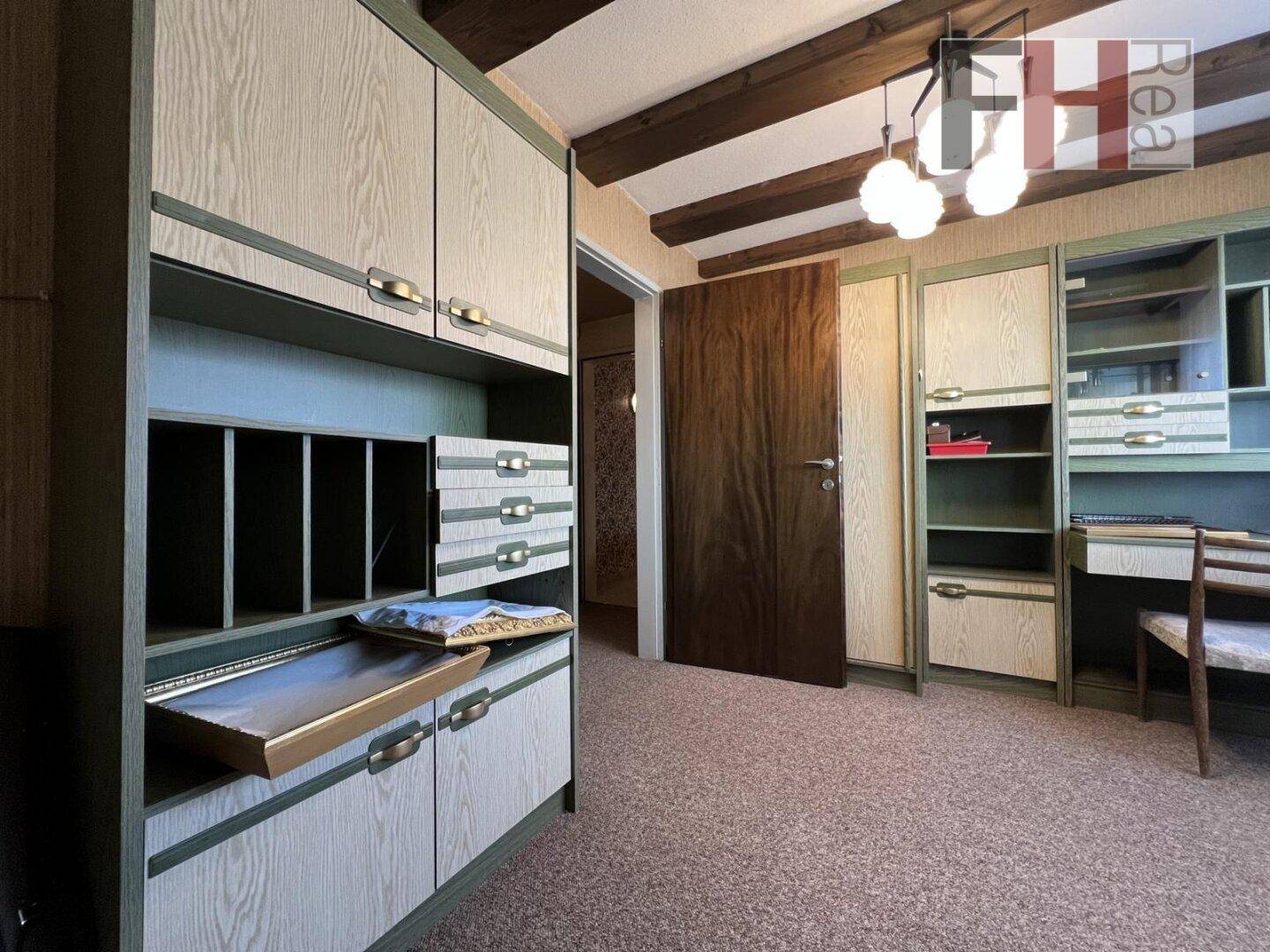 Schlafzimmer im Dachgeschoss mit Einbauschränken, Schrägen und Teppichboden.