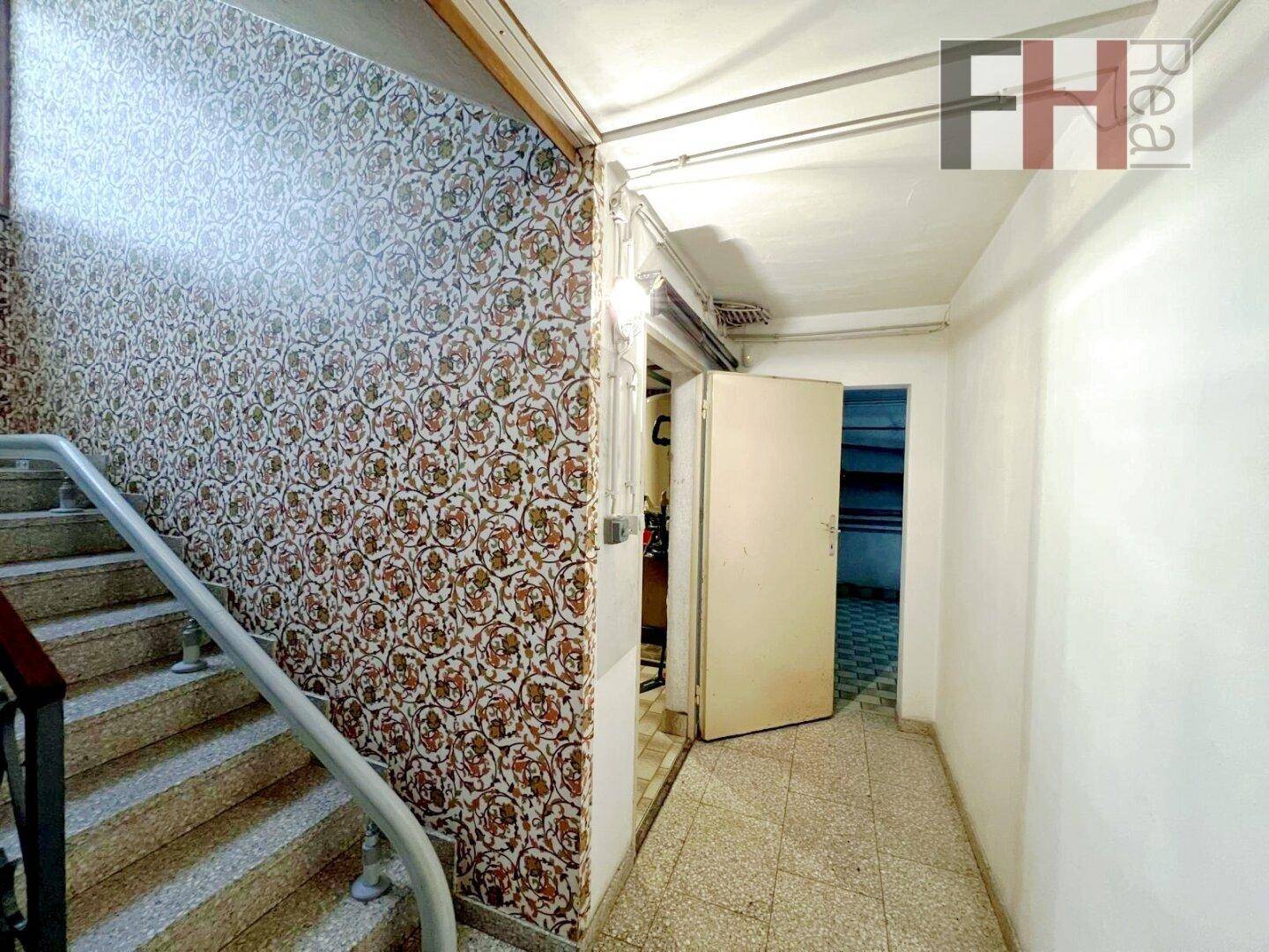 Treppenhaus im Kellergeschoss mit Fliesenboden und Zugang zu weiteren Räumen.