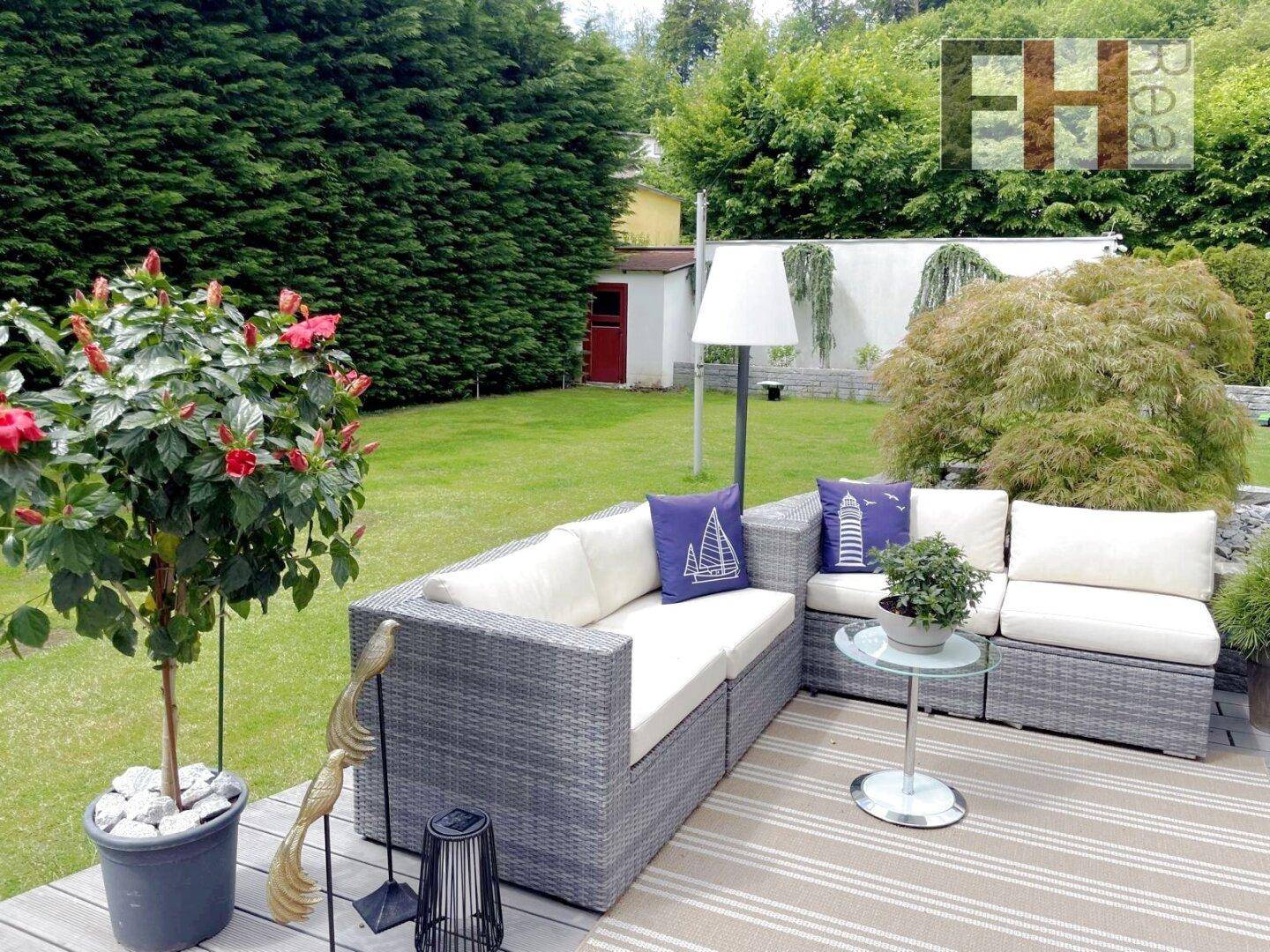 Gemütliche Lounge-Ecke im grünen Garten mit bequemen Sitzmöbeln und dekorativen Pflanzen.