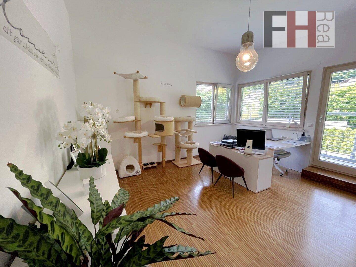 Helles Arbeitszimmer mit Holzboden, großem Schreibtisch und vielen Fenstern für Tageslicht.