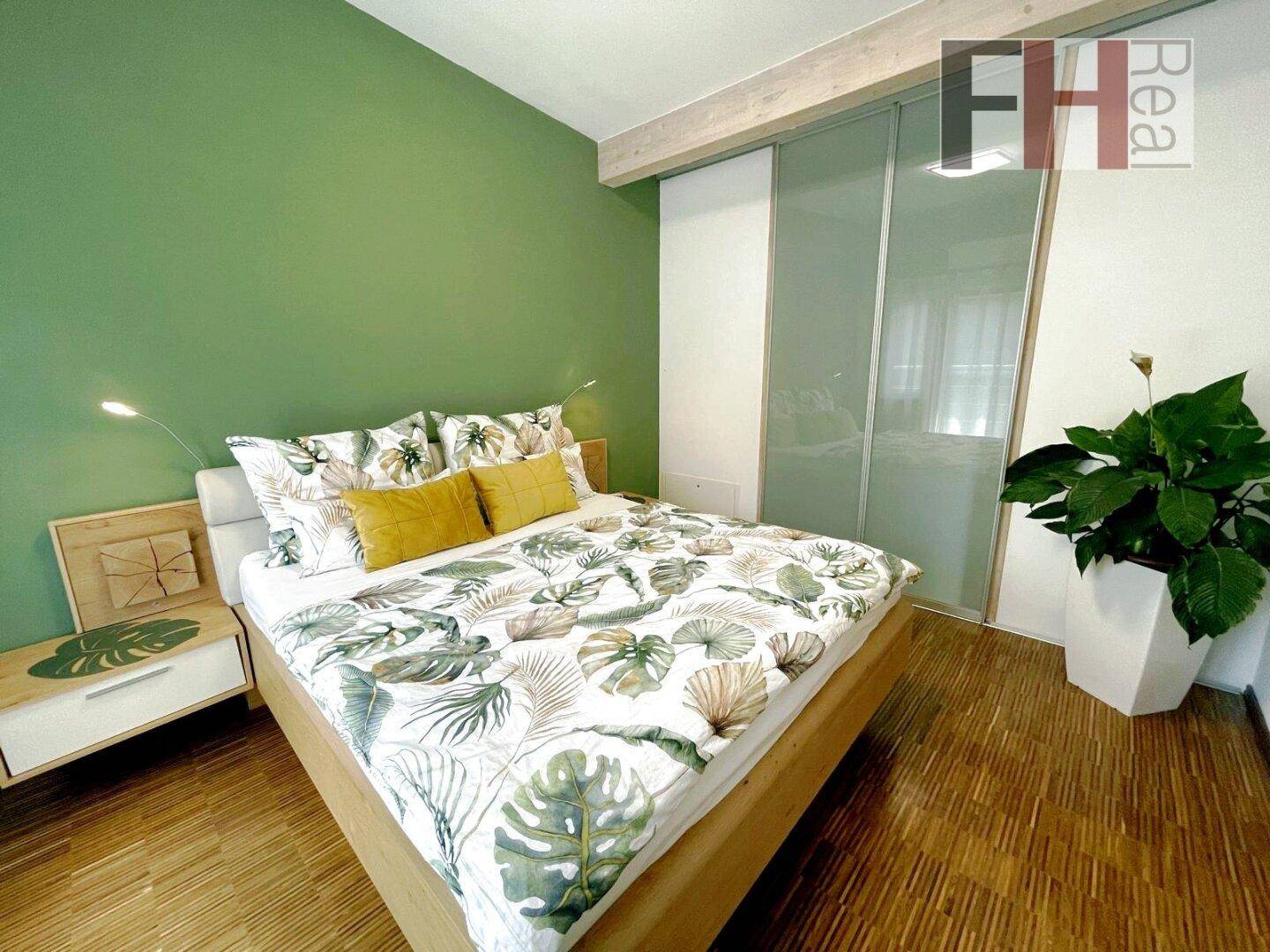 Gemütliches Schlafzimmer mit grün gestrichener Wand, Holzboden und großem Bett.