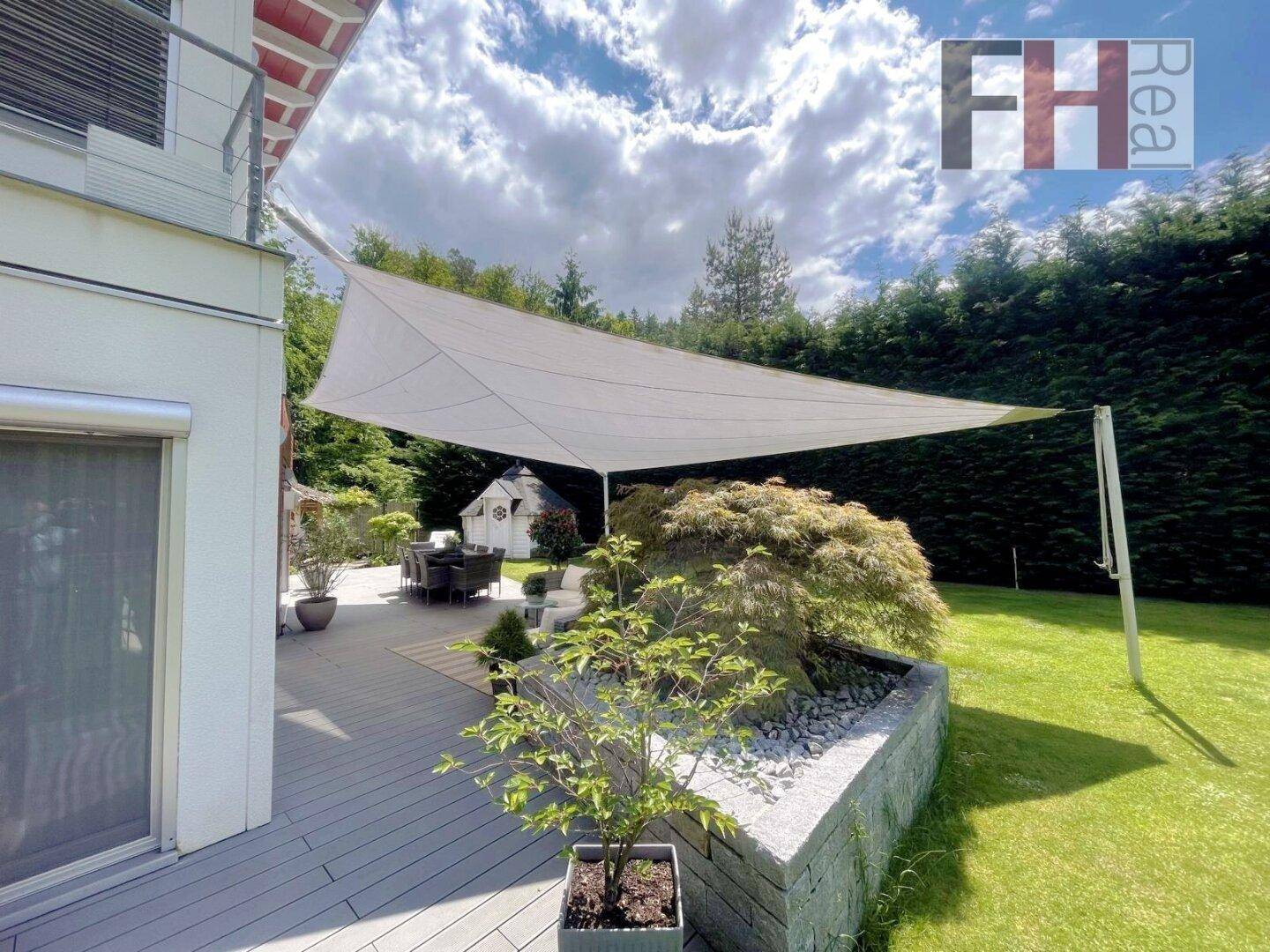Große Terrasse mit Sonnensegel, Gartenmöbeln und Blick ins Grüne.