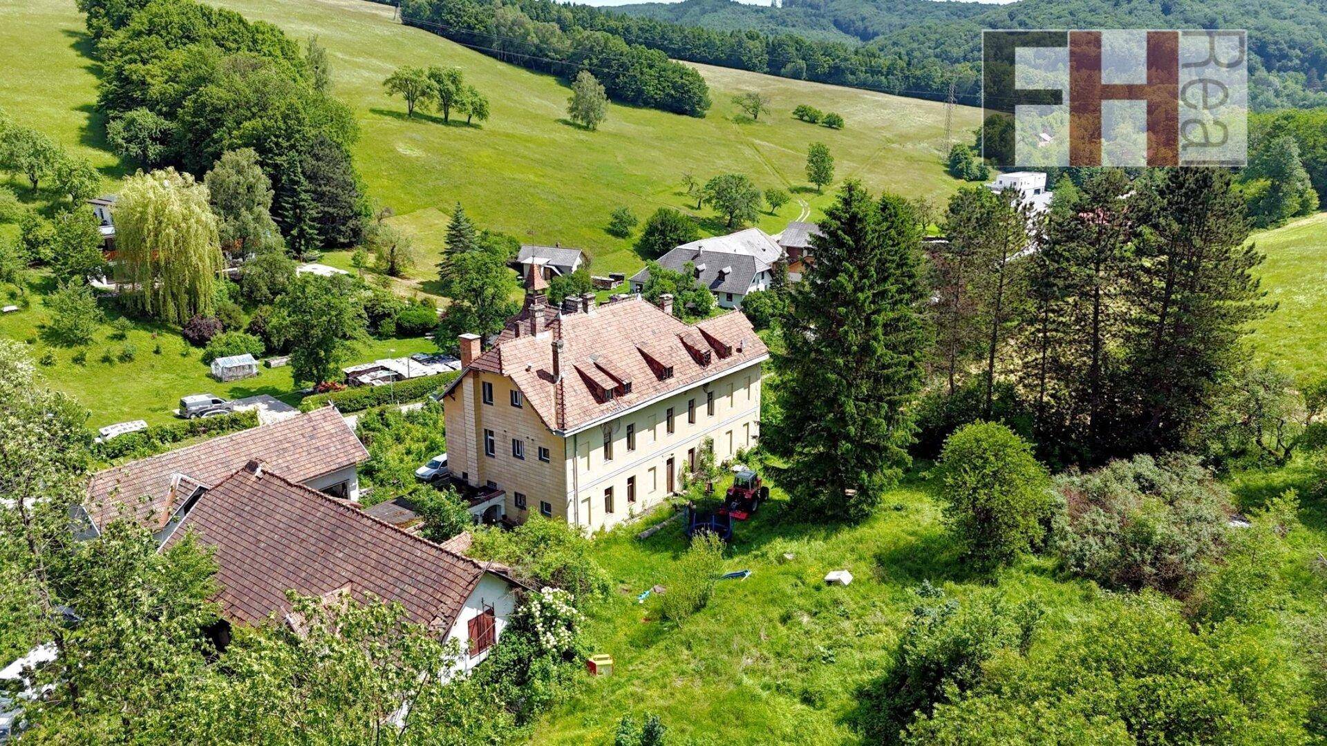 Luftaufnahme des Anwesens mit umliegenden Häusern und der weiten grünen Landschaft.