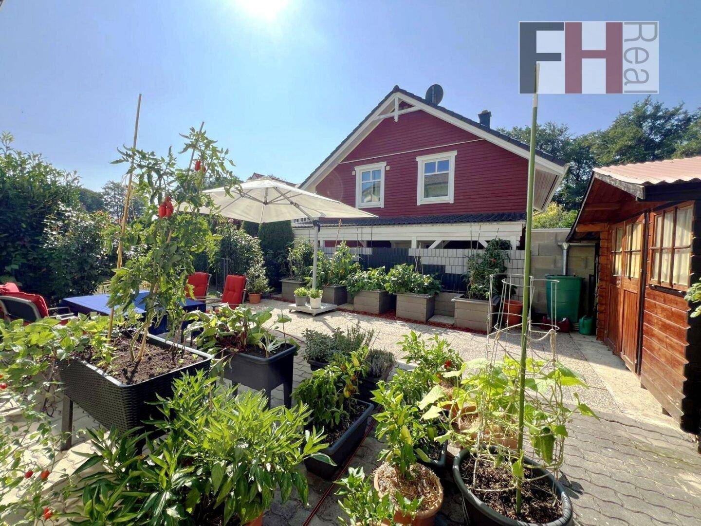 Gemütlicher Terrassenbereich mit vielen Pflanzen, Esstisch und Blick auf das charmante rote Nachbarhaus.