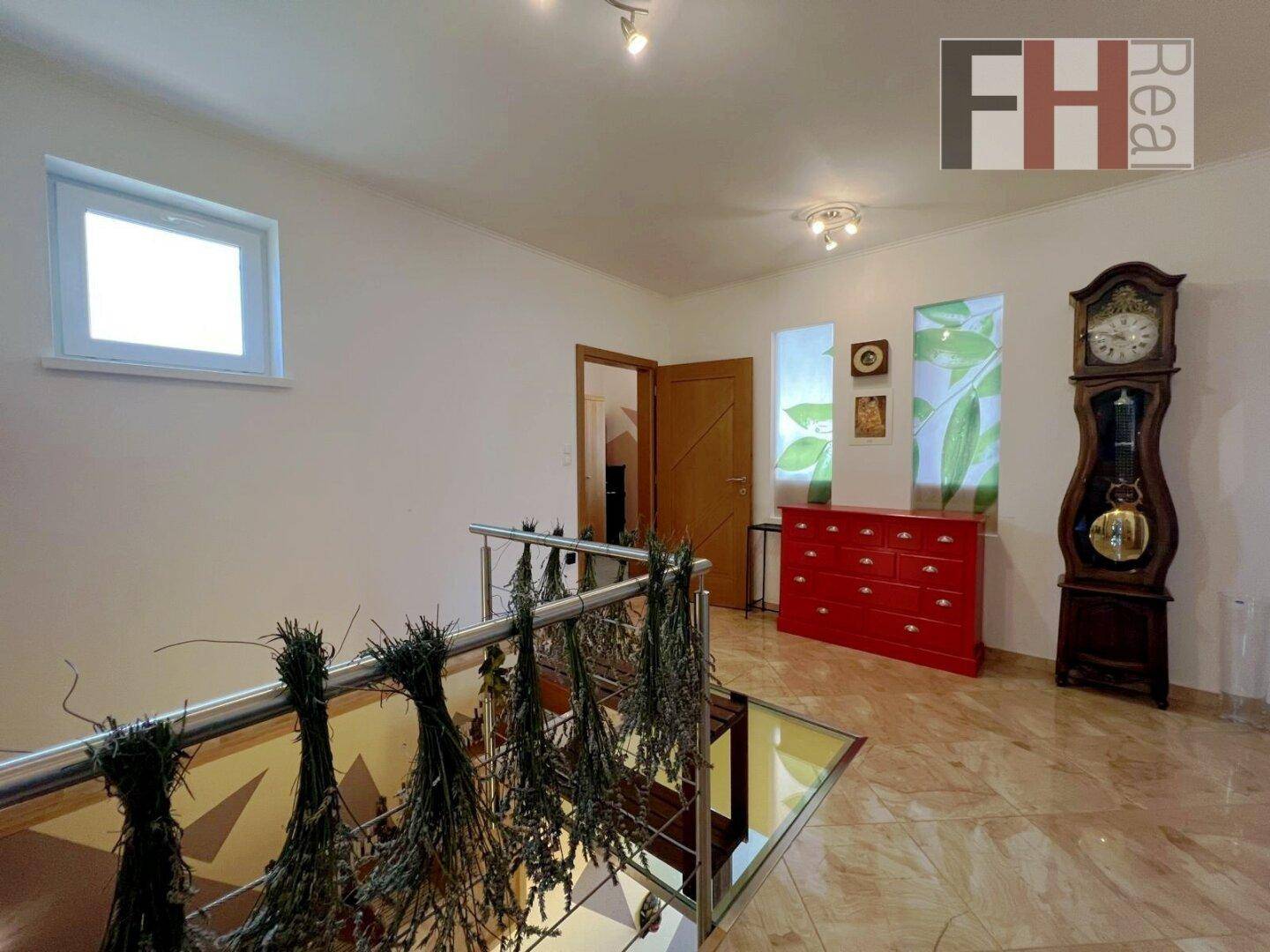 Heller Flur mit Fliesenboden, Glasbodenelement und einem Fenster, das Tageslicht hereinlässt.