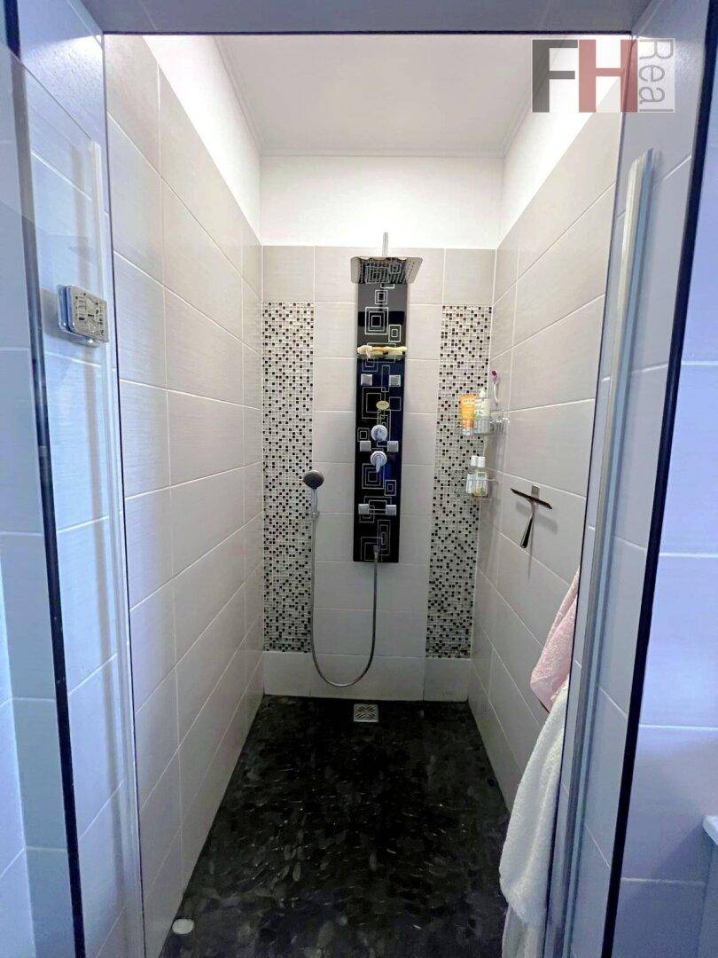 Geräumige begehbare Dusche mit modernem Duschpaneel und dunklem Fliesenboden.