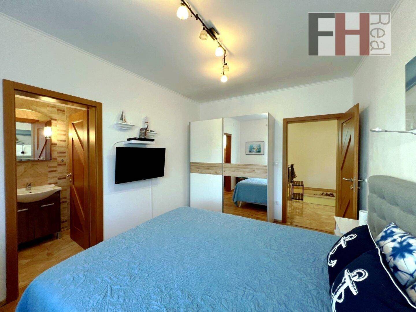 Schlafzimmer mit Bett, Spiegelschrank und direktem Zugang zu einem eigenen Badezimmer.