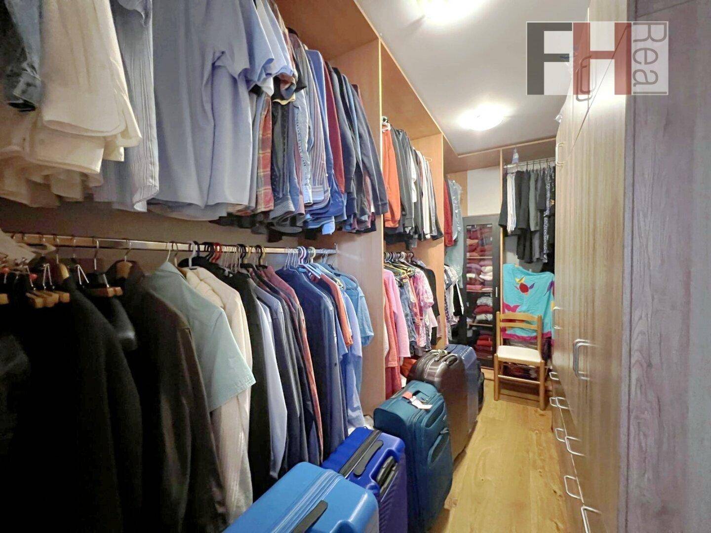Begehbarer Kleiderschrank mit viel Stauraum und Regalen für Kleidung und Gepäck.