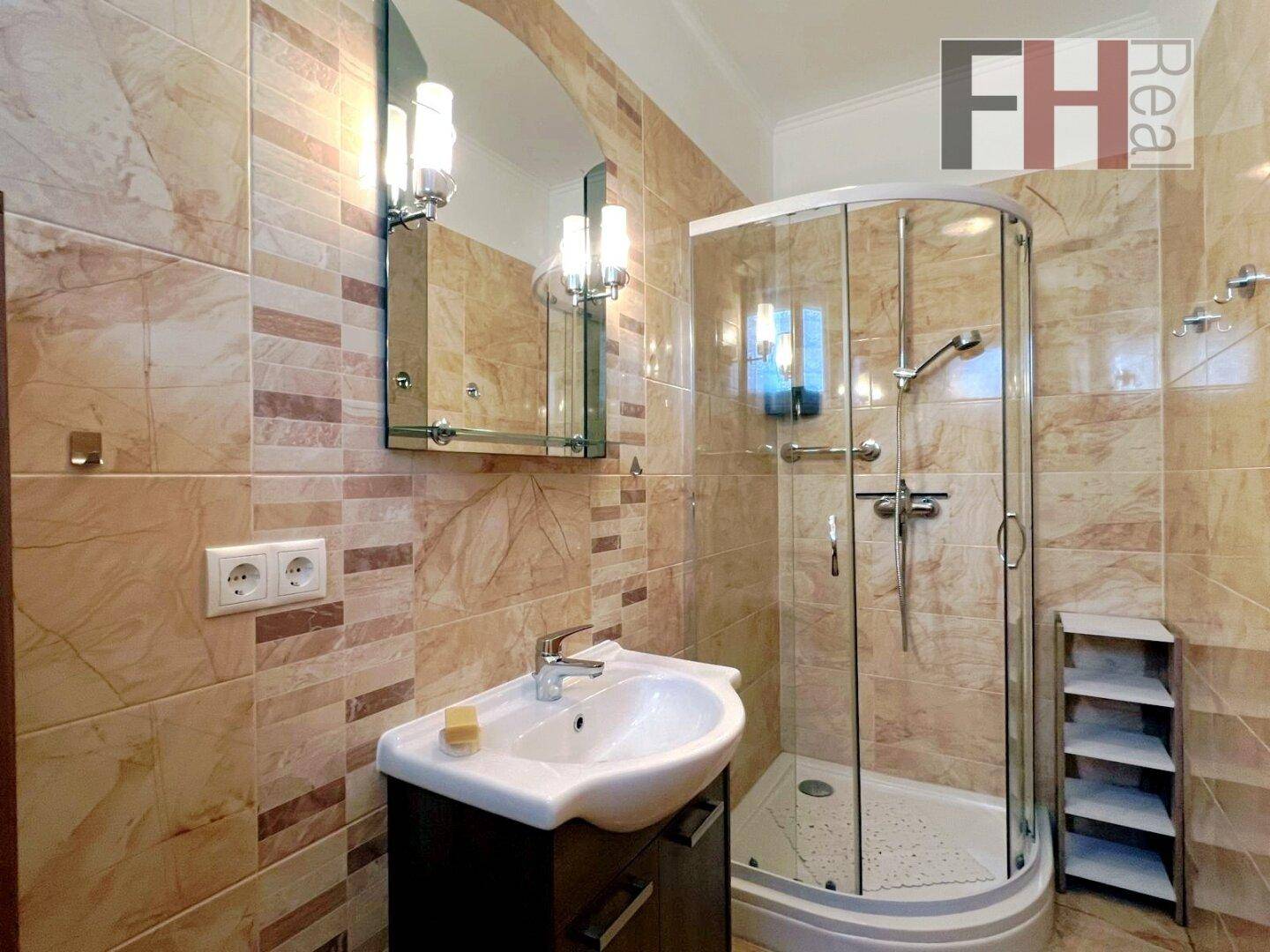 Modernes Badezimmer mit beigefarbenen Fliesen, Duschkabine und Einzelwaschbecken.