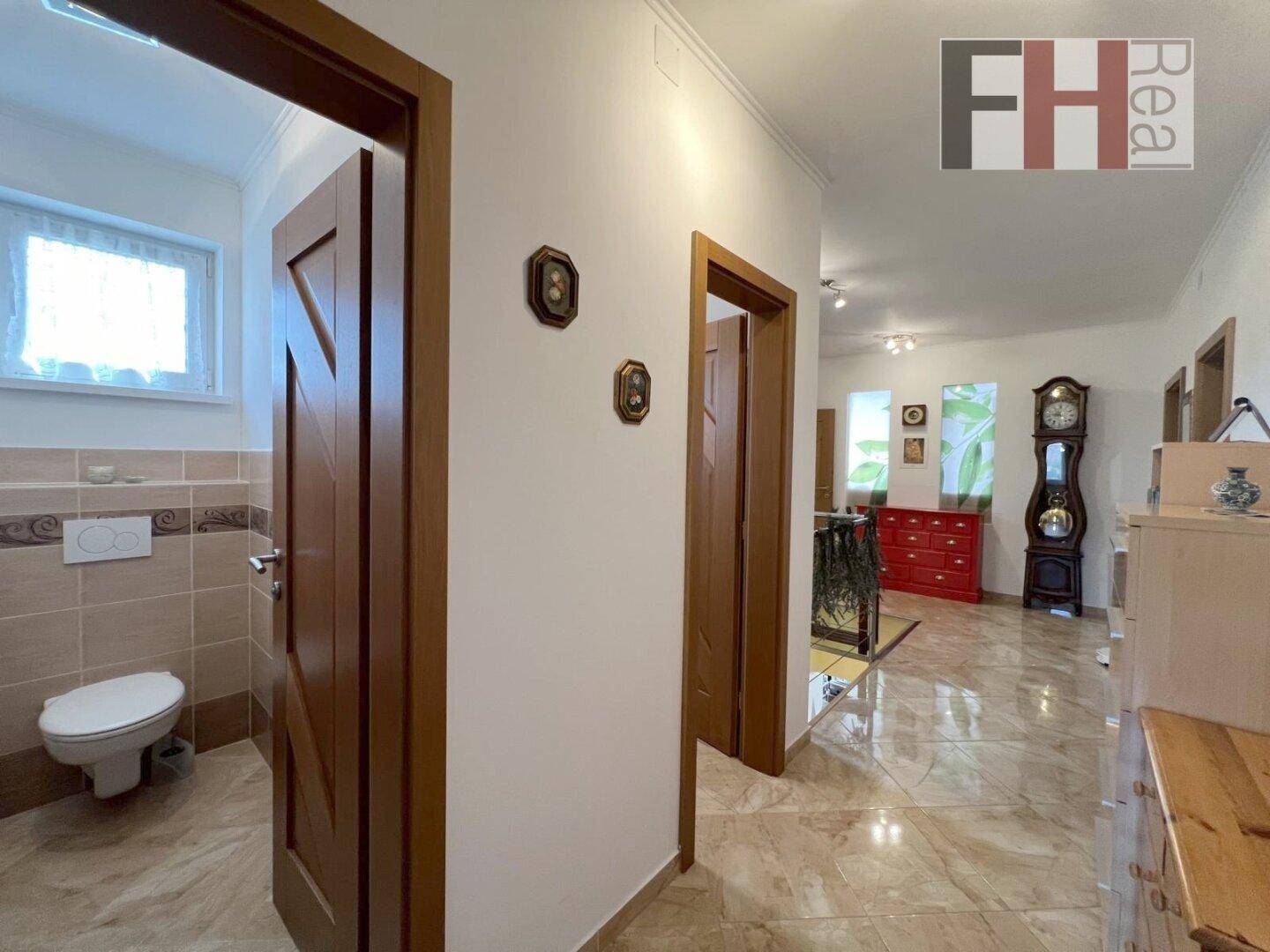 Heller Flur mit Fliesenboden, Holztüren und Blick in angrenzende Räume.